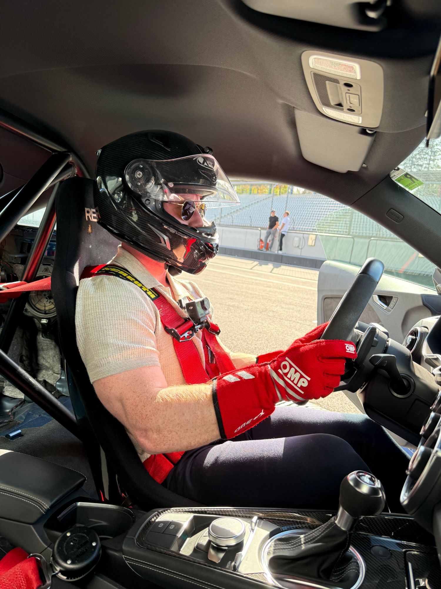 Nino Kuhn im Cockpit eines Rennwagens mit Helm und Renngurt an der Strecke